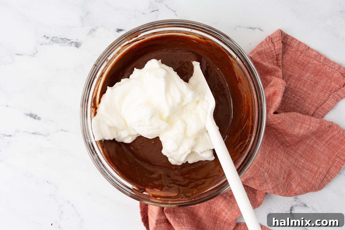 Silken Chocolate Indulgence 7 A rubber spatula gently folding airy whipped egg whites into the chocolate and egg yolk base, illustrating the technique to maintain lightness.