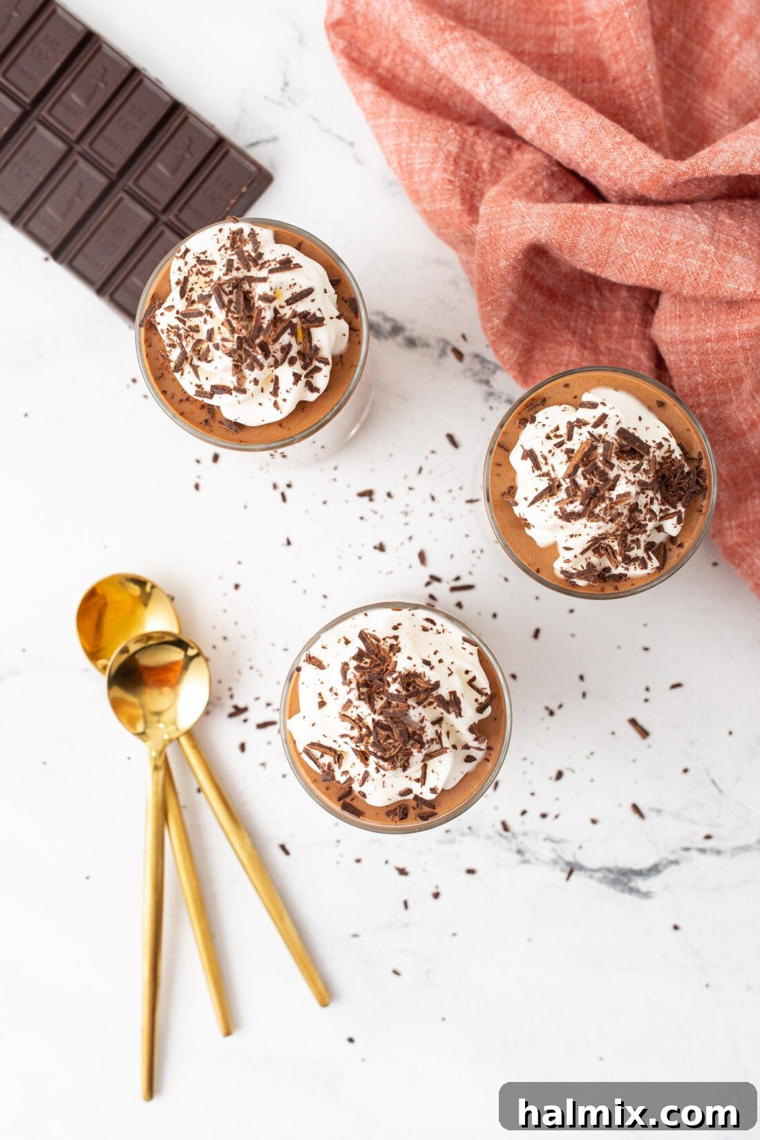 Silken Chocolate Indulgence 9 Overhead shot of multiple individual servings of chocolate mousse in elegant glasses, garnished with whipped cream and fine chocolate curls.