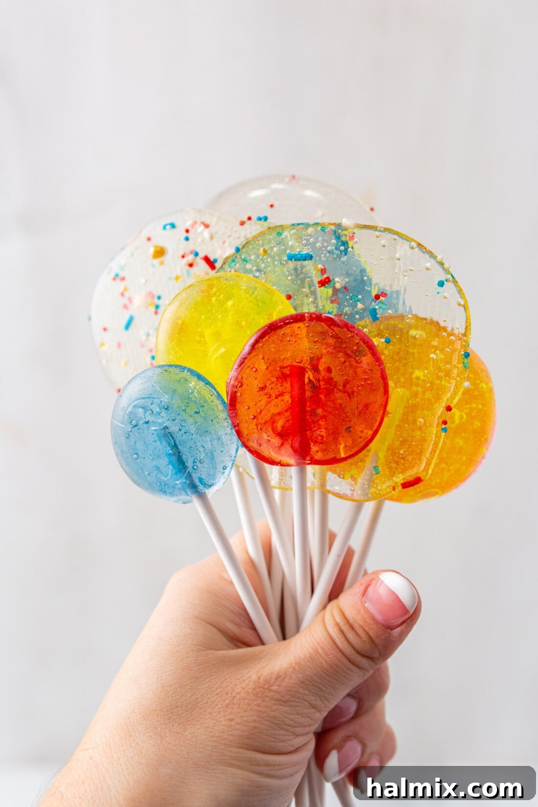 Hand holding a bunch of freshly made homemade lollipops in various colors and flavors