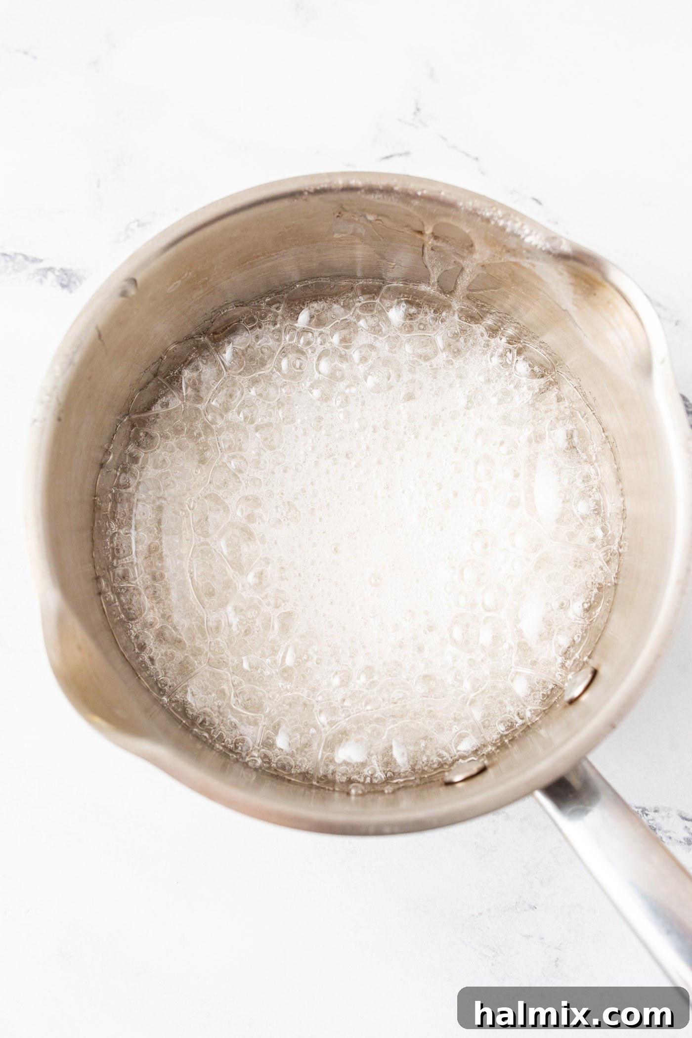 Lollipop candy syrup boiling vigorously in a pot on the stovetop