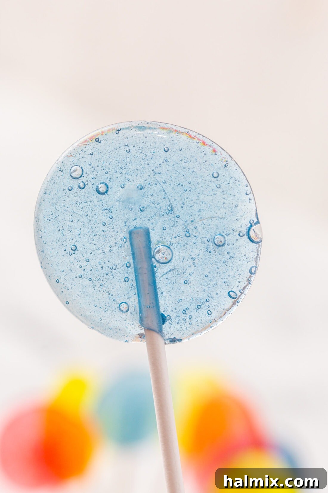 A single pink homemade lollipop with a stick, standing upright