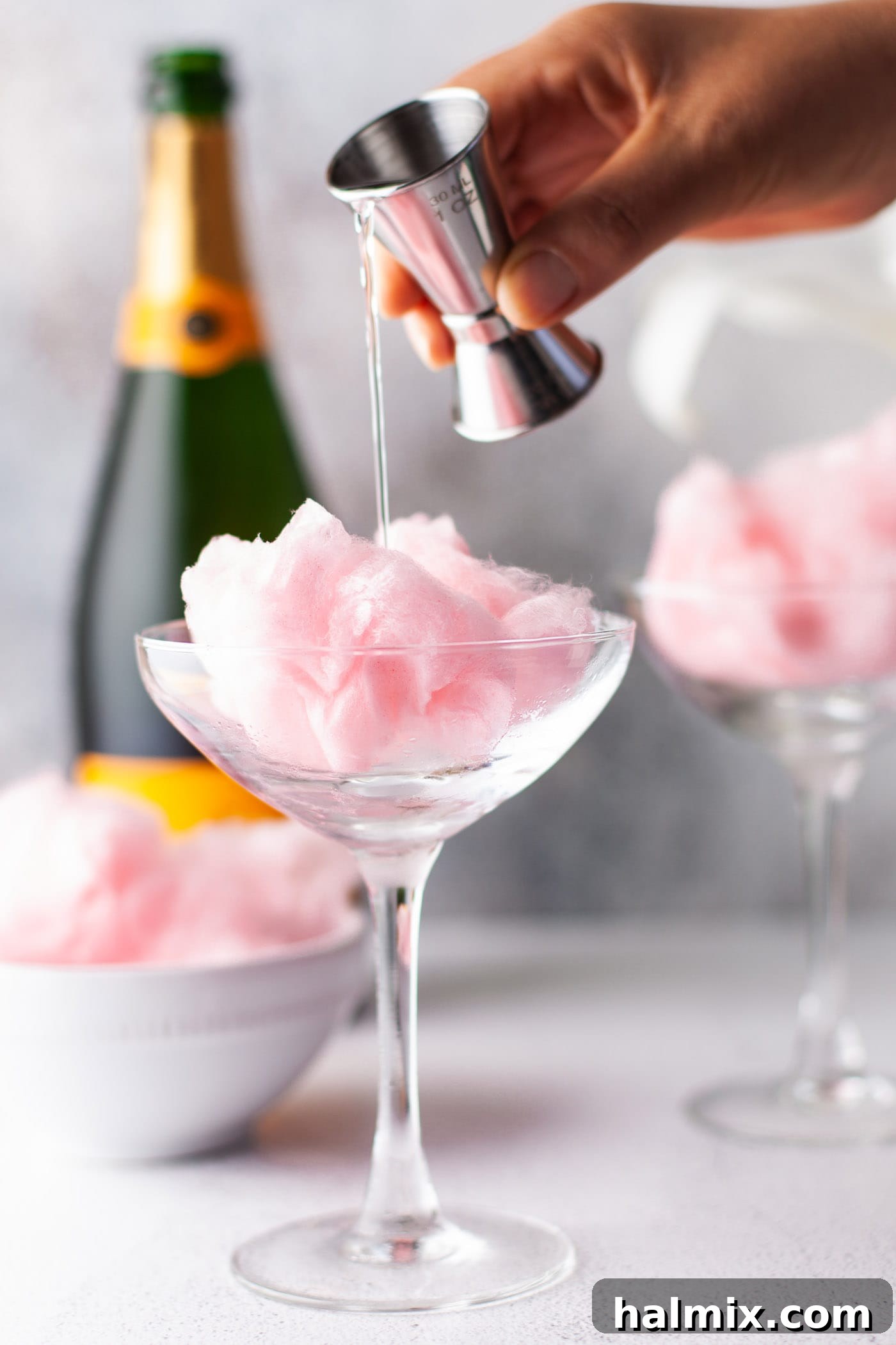 Sweet Cloud Sparkle 4 hand pouring orange liquor into glass of cotton candy