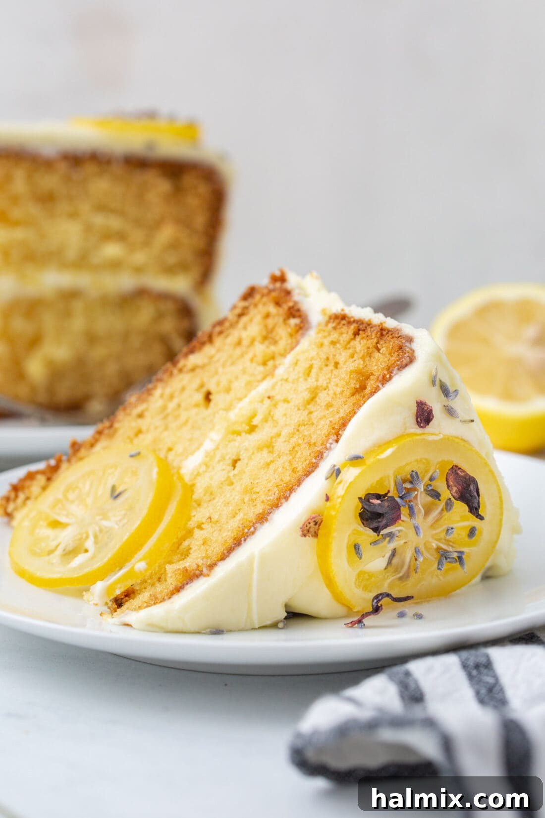A perfectly cut slice of lemon cake on a white plate, showing the fluffy frosting and moist cake texture.