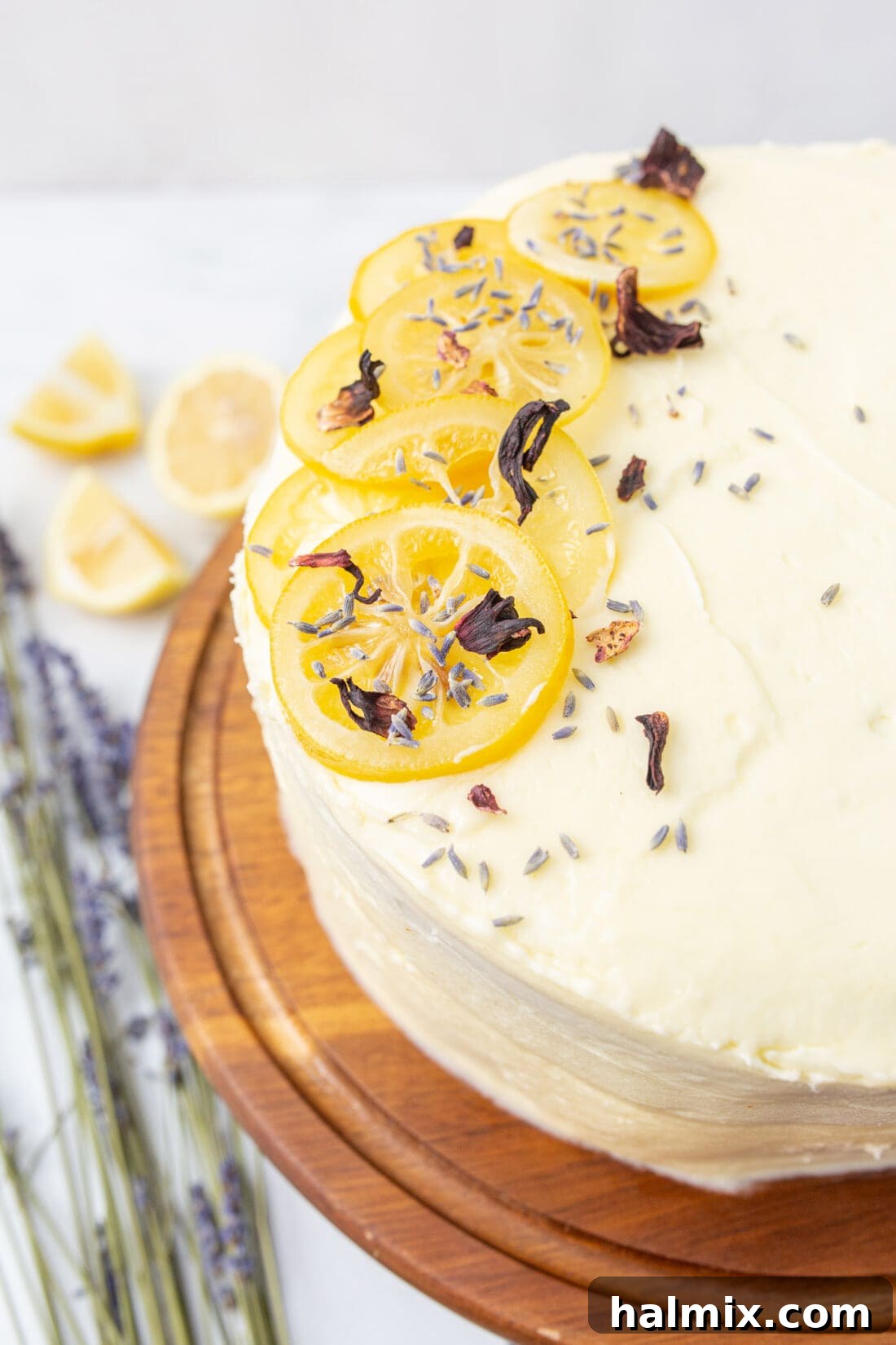 A beautifully decorated tiered lemon cake displayed on an elegant cake plate.