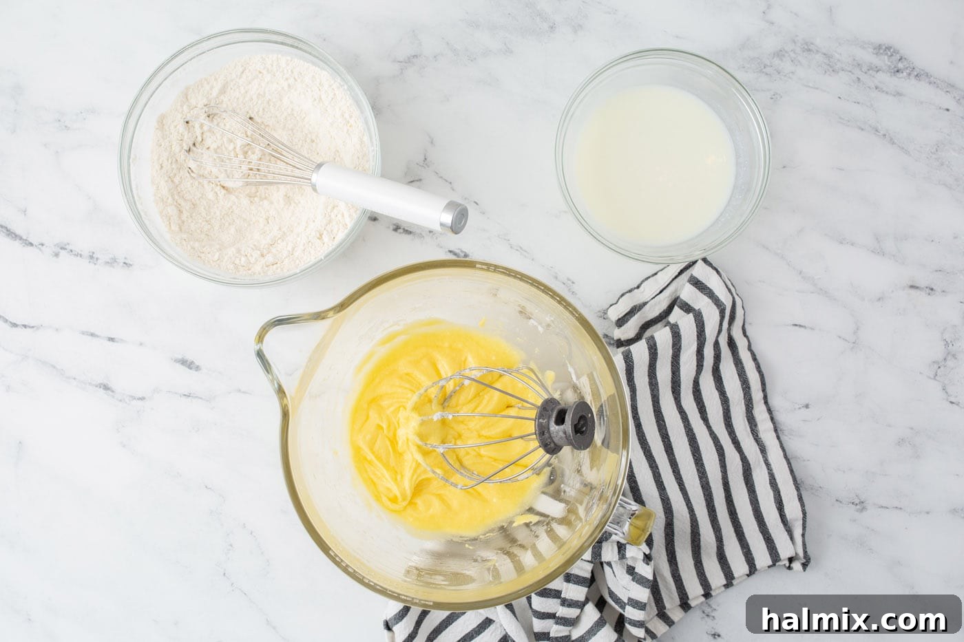 Lemon cake ingredients being mixed in bowls, showing the process of combining wet and dry ingredients.