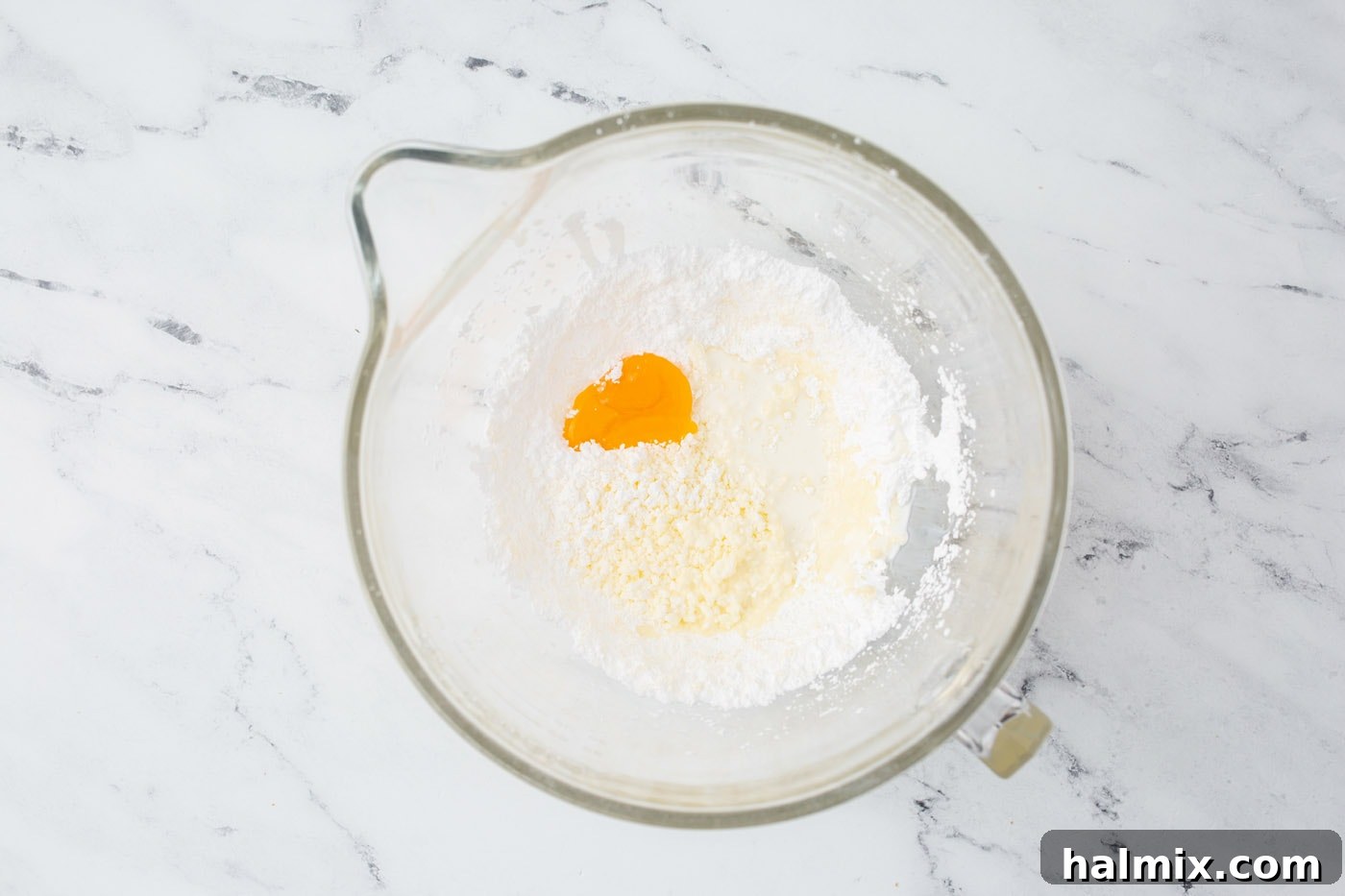 Ingredients for lemon frosting in a mixing bowl before being fully combined.