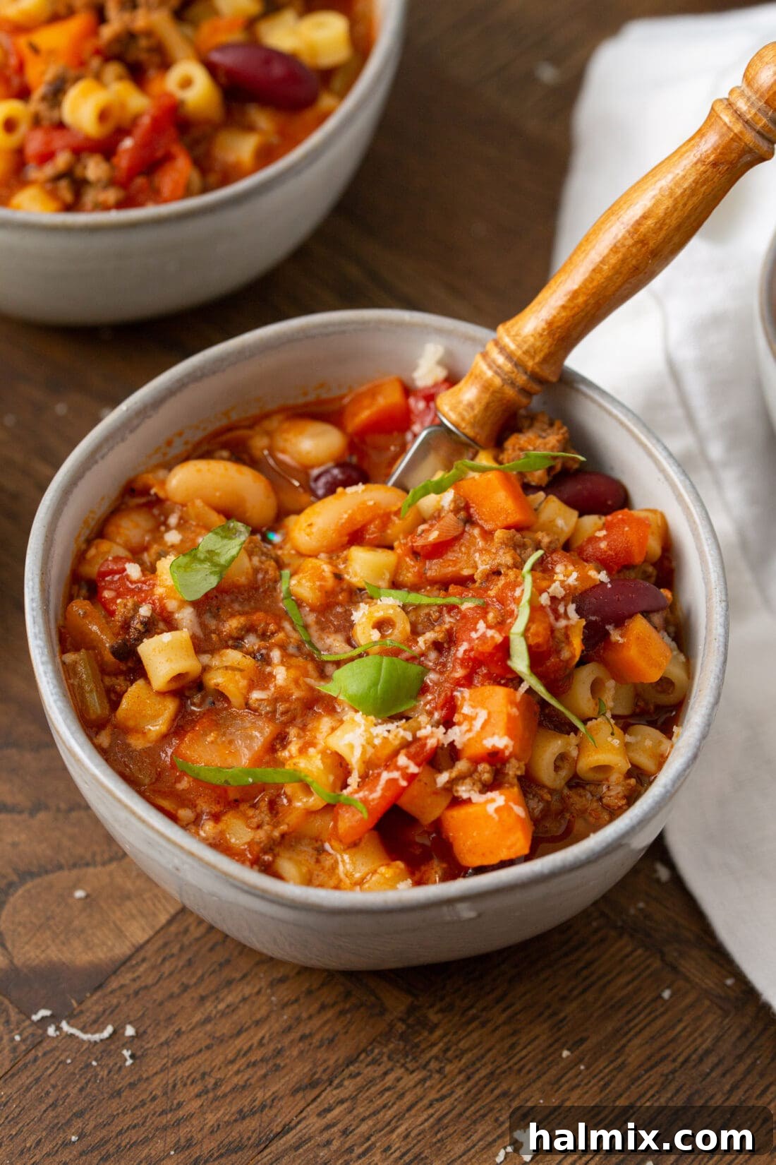 A steaming bowl of hearty Pasta Fagioli soup garnished with fresh herbs.