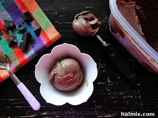 Two scoops of Black Cow Ice Cream, one in a bowl with a spoon, the other freshly scooped and resting on an ice cream scooper beside it.