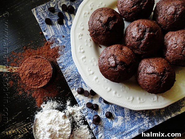 Starbucks Hot Cocoa Chocolate Chip Muffins An overhead photo of Starbucks hot cocoa chocolate chip muffins on a white plate with cocoa and flour to the side, ready for baking.