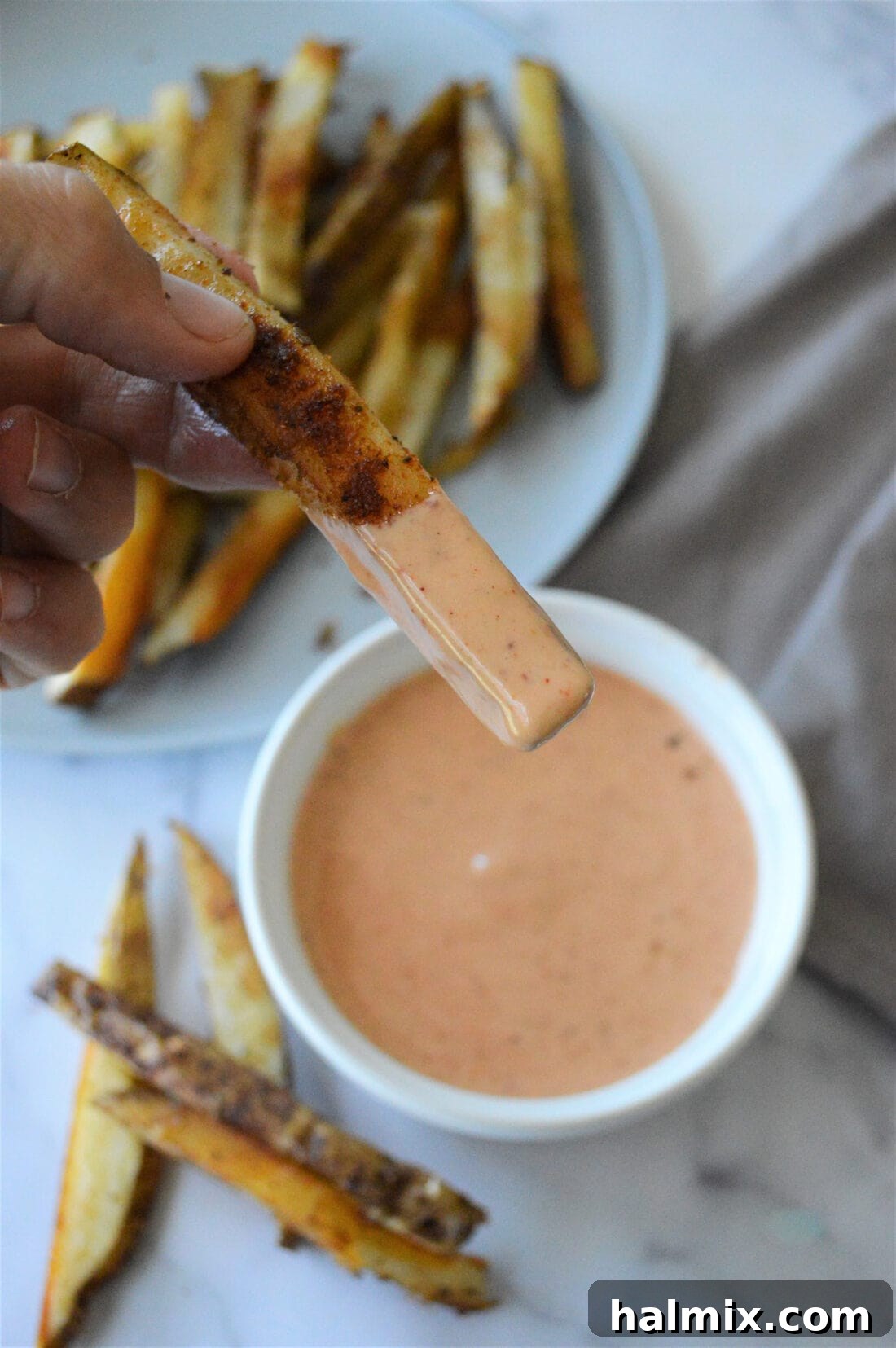 Golden French fry being dipped into the delectable Homemade French Fry Sauce