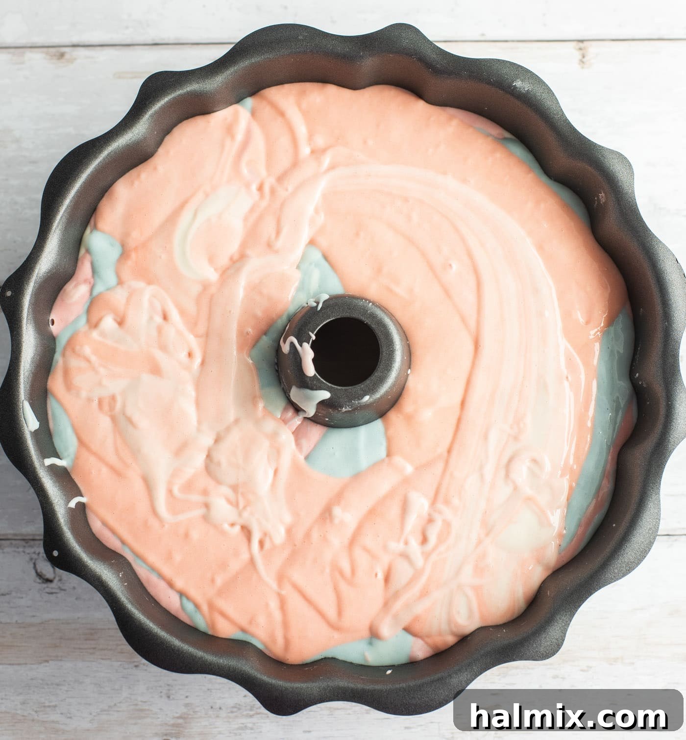 All pastel colored cake batter elegantly swirled in the bundt pan, showcasing the layered design, ready for baking.