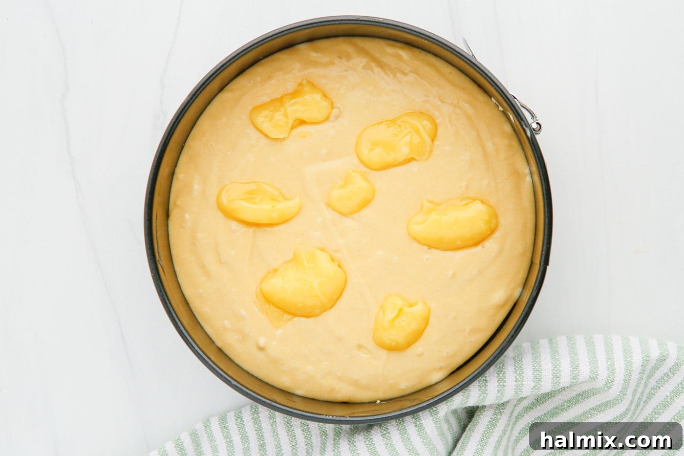 Zesty Instant Pot Lemon Cake 5 Dollops of vibrant yellow lemon curd placed on top of unbaked lemon cake batter in a springform pan.