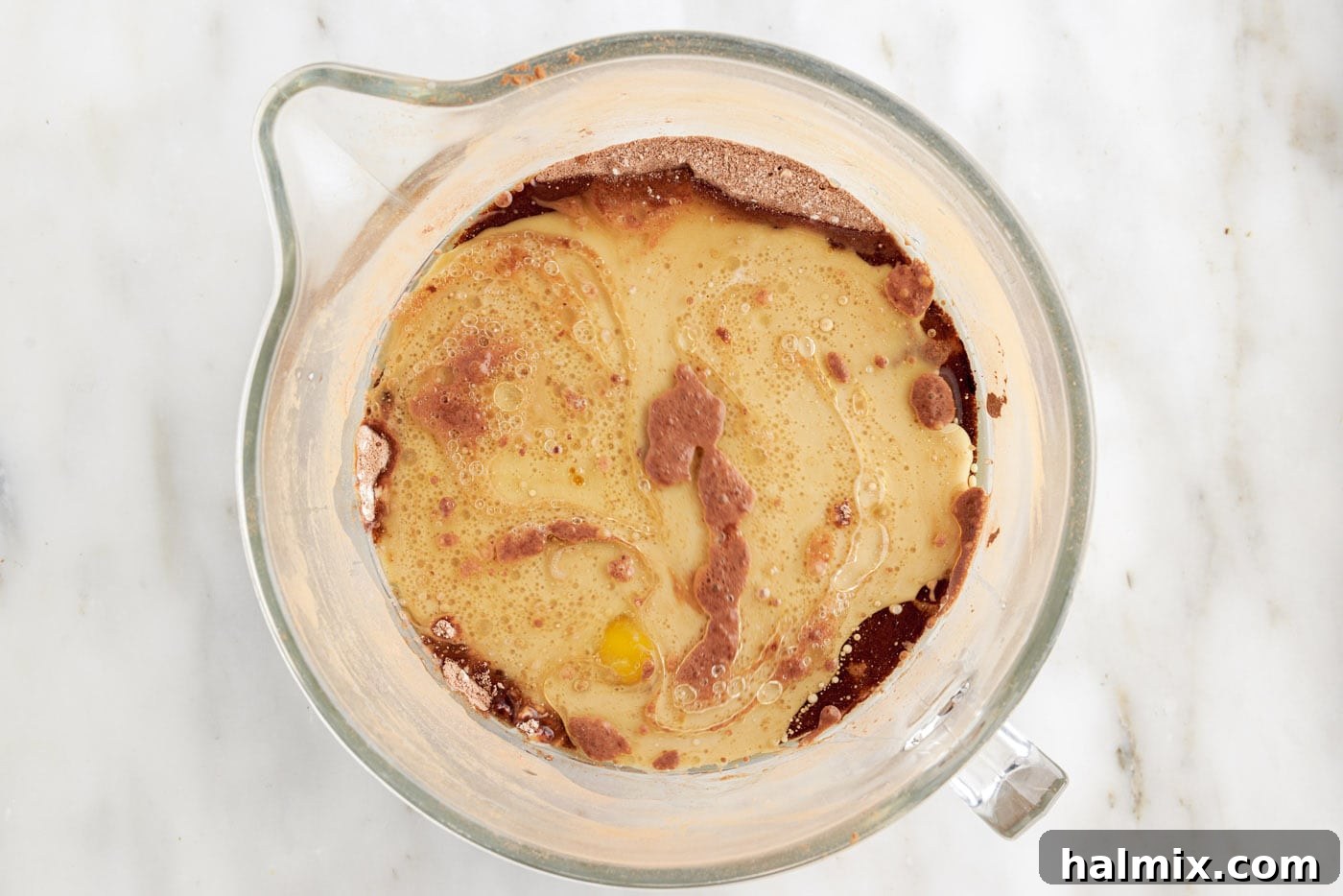 Decadent Double Chocolate Delights 6 adding wet ingredients to dry ingredients for cupcake batter in a large mixing bowl.
