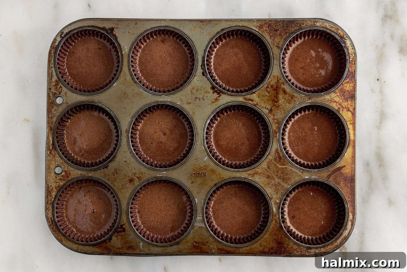 Decadent Double Chocolate Delights 8 chocolate cupcake batter evenly distributed into a muffin tin with liners.