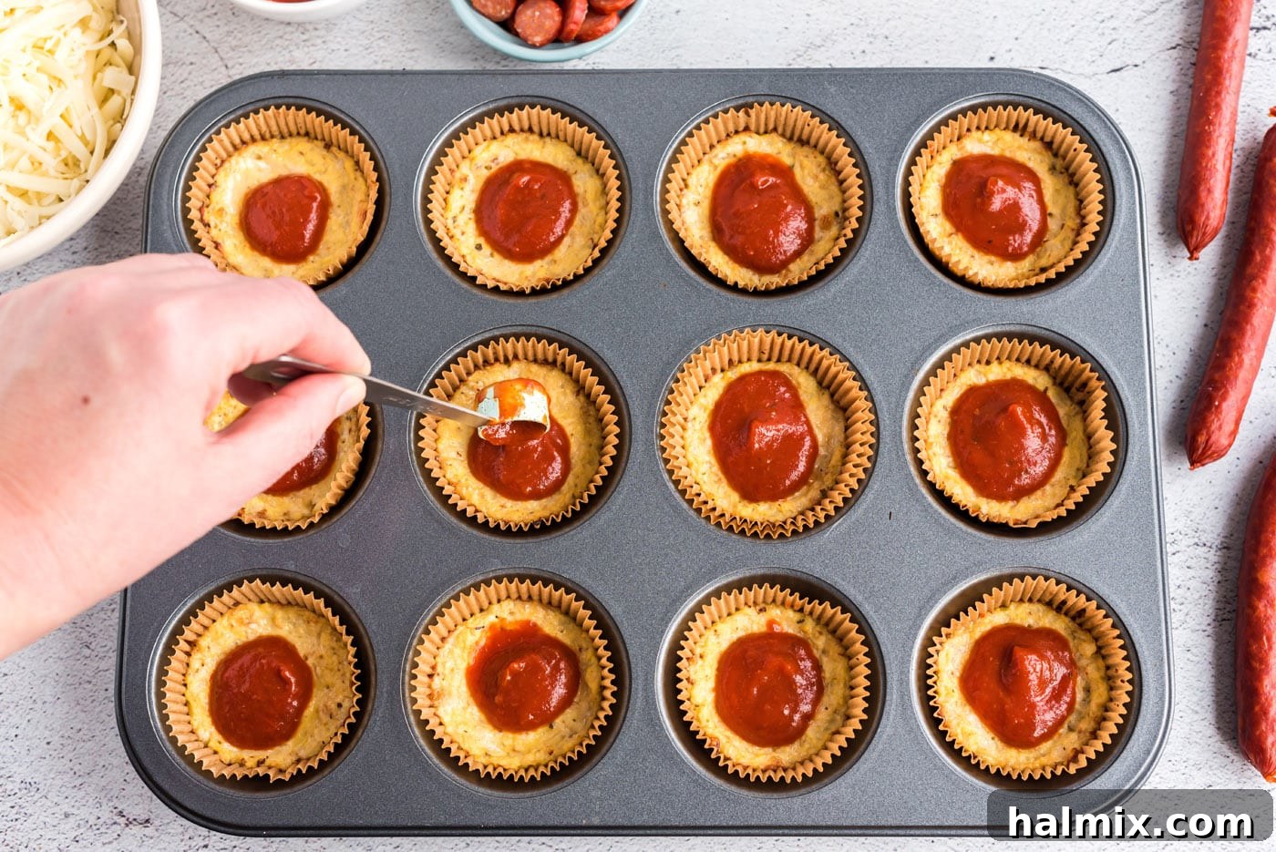 Cauliflower Pizza Poppers 7 spooning pizza sauce on top of cauliflower pizza bites