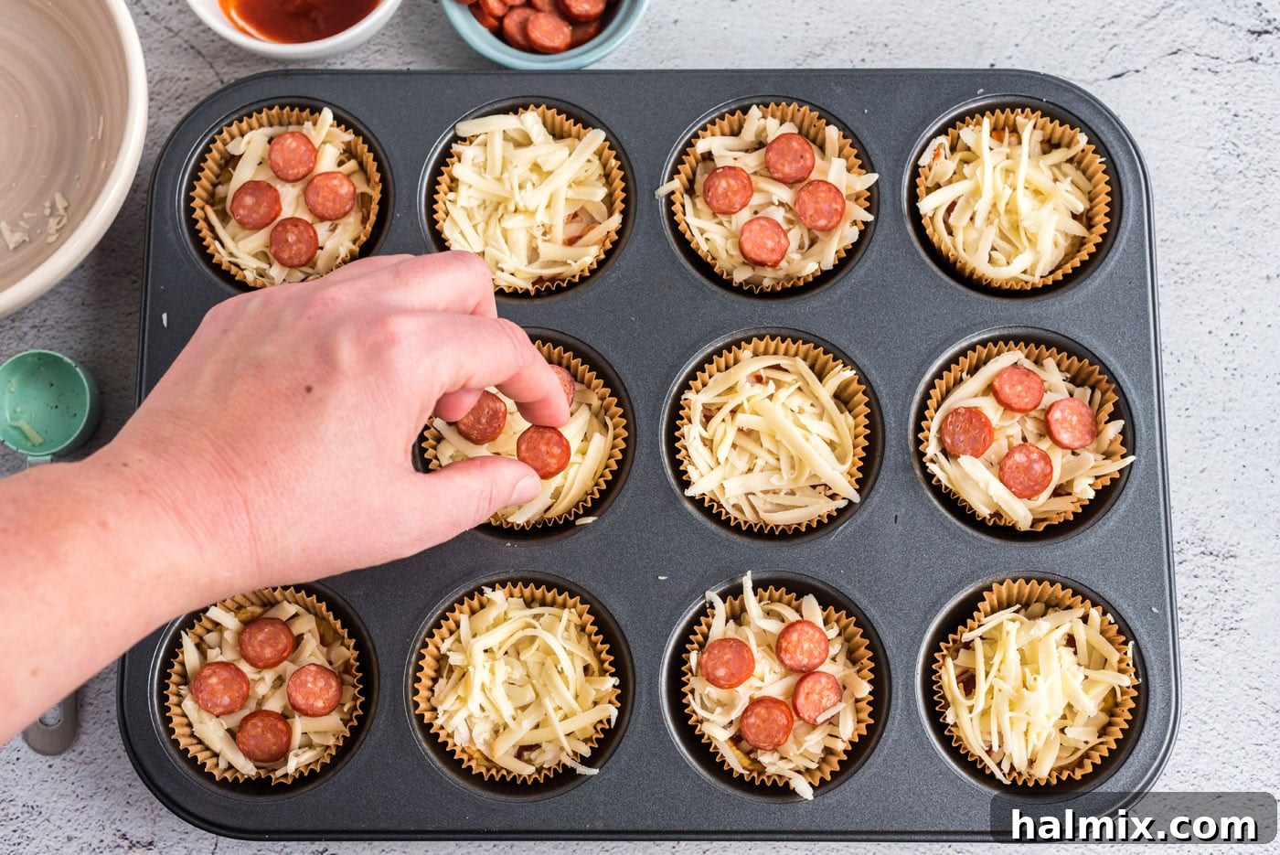 Cauliflower Pizza Poppers 9 hand adding mini pepperoni to pizza bites