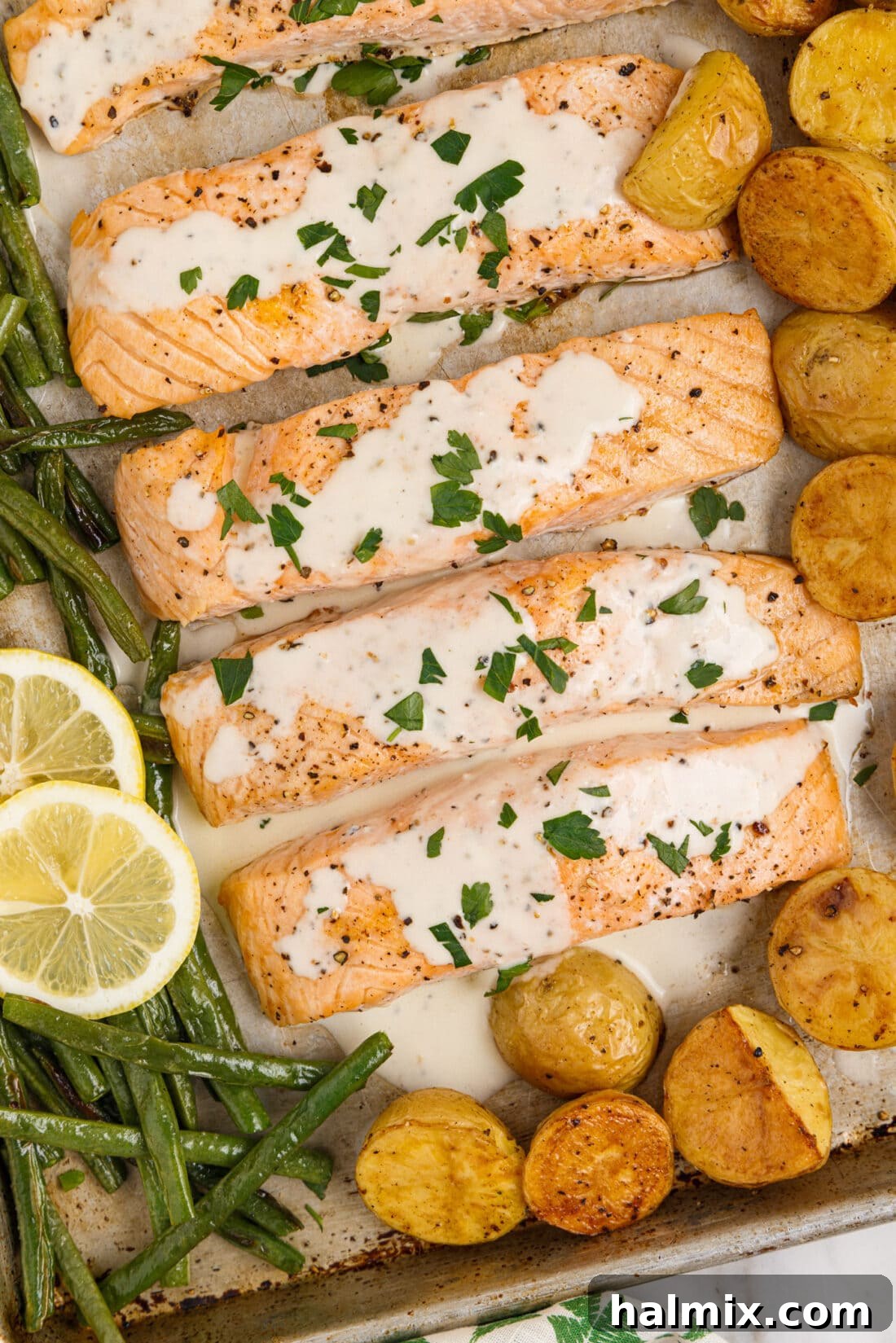 Close-up shot of a perfectly baked salmon fillet with lemon cream sauce and fresh parsley garnish.