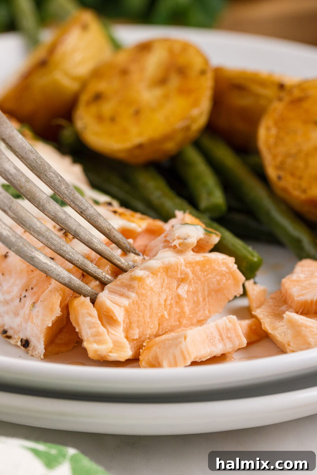 A fork gently flaking a piece of perfectly baked salmon, showing its tender texture.