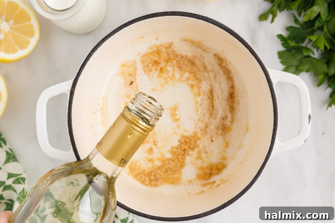 Pouring dry white wine into the saucepan with sautéed garlic and butter.