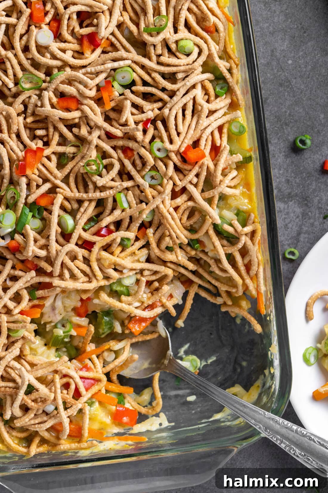 A golden-brown Chicken Chow Mein Casserole with a serving spoon, ready to be dished out, highlighting its creamy texture and crunchy topping.