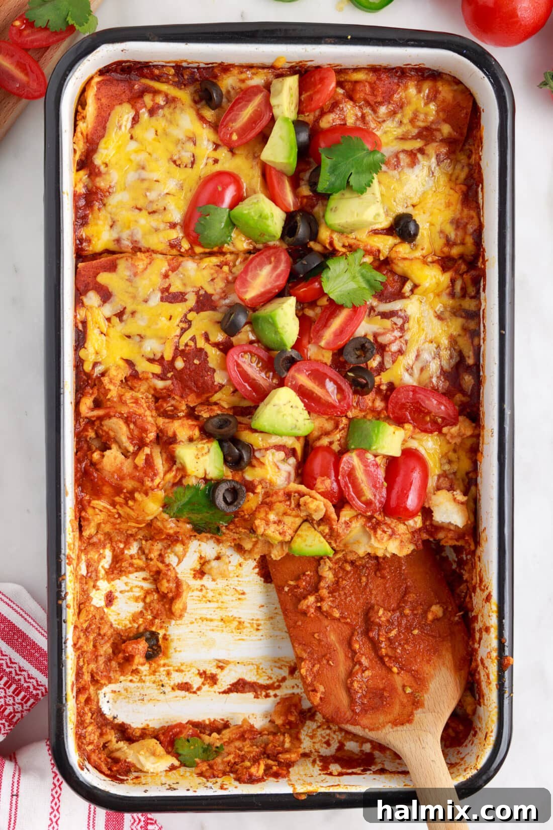 Serving a generous piece of Chicken Enchilada Casserole from a baking dish.