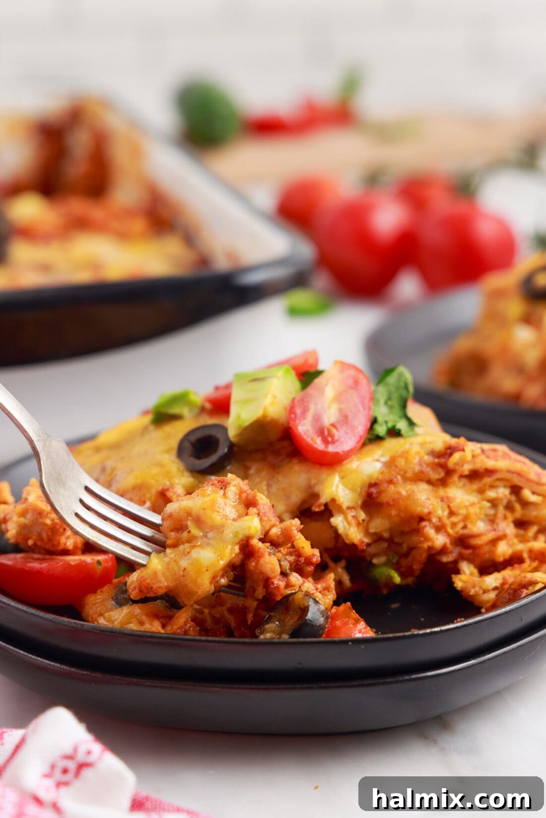 A single serving of Chicken Enchilada Casserole on a white plate with a fork.