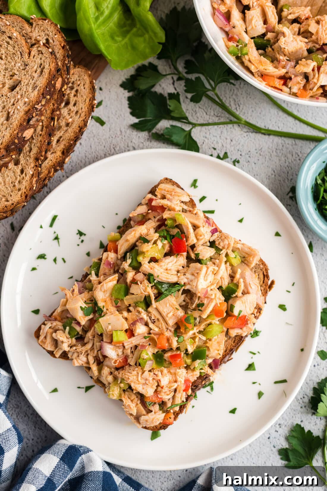Cajun Chicken Salad served on a slice of rustic bread, garnished with fresh herbs