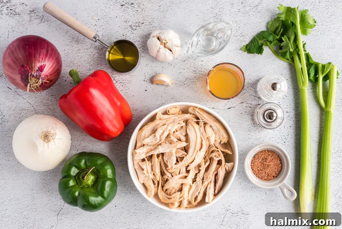 All ingredients for Cajun Chicken Salad laid out on a table, including chopped chicken, vegetables, and dressing components