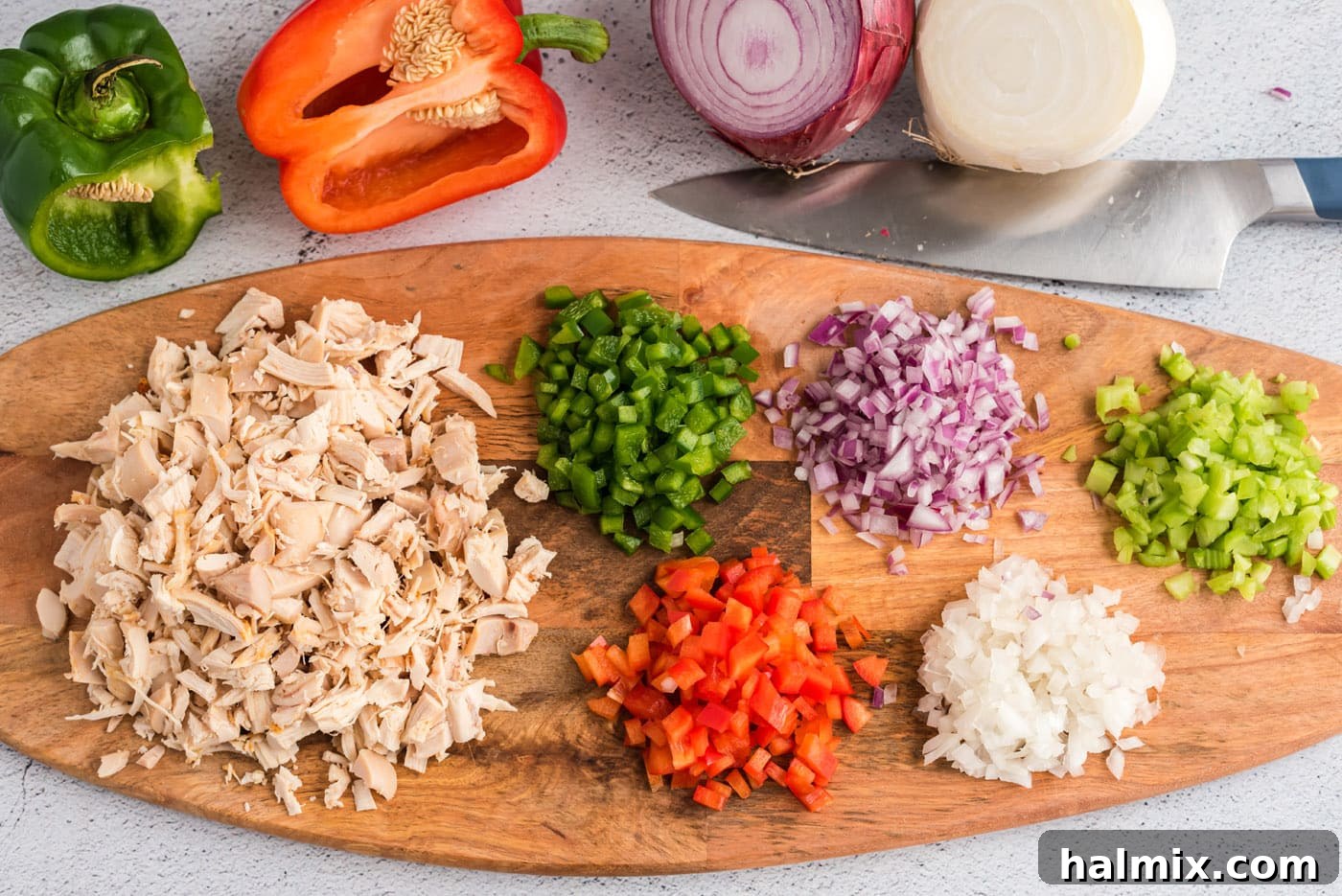 Chopped chicken, celery, onions, and bell peppers on a cutting board, ready for mixing