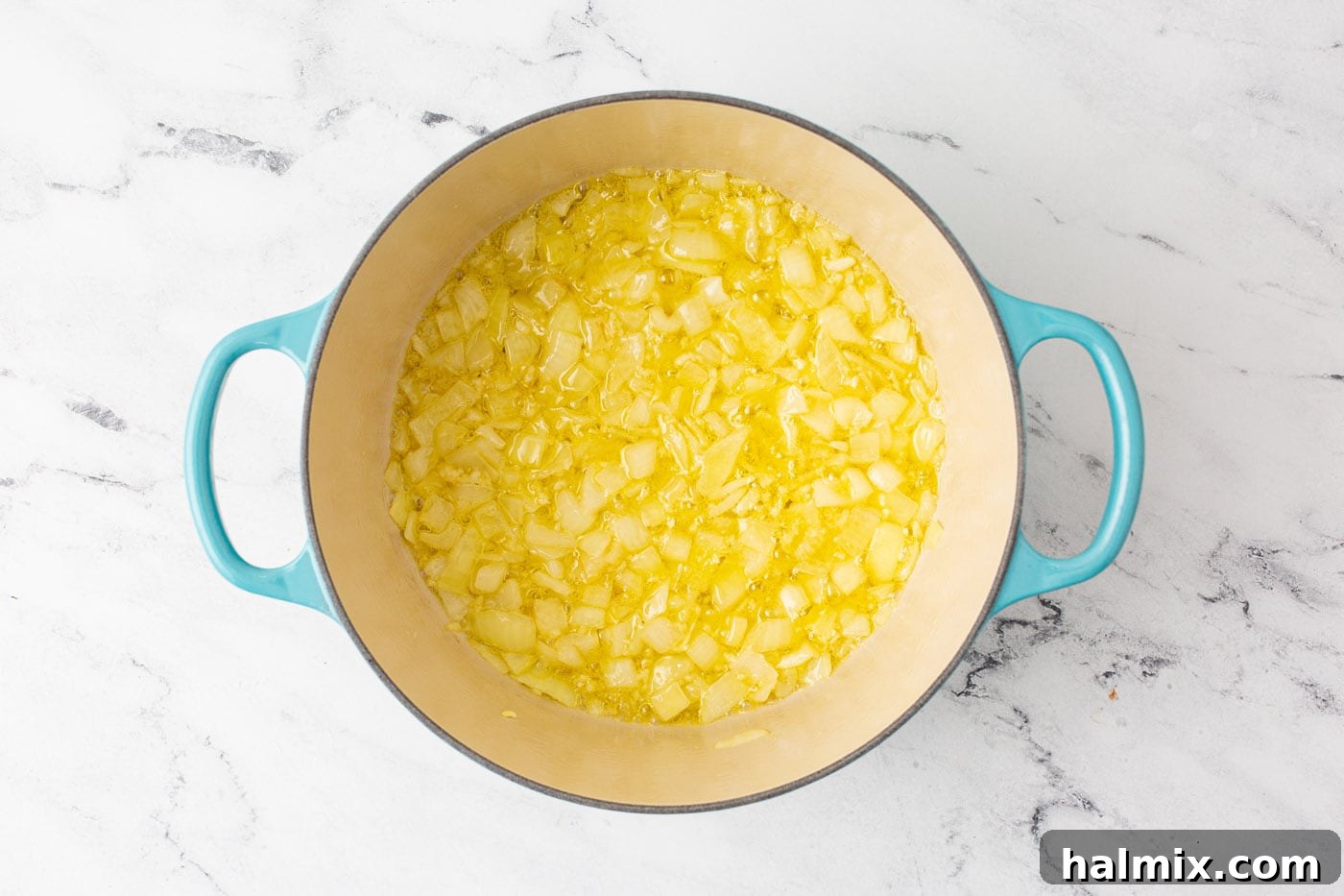 Finely chopped yellow onion cooking in melted butter and olive oil in a large Dutch oven.