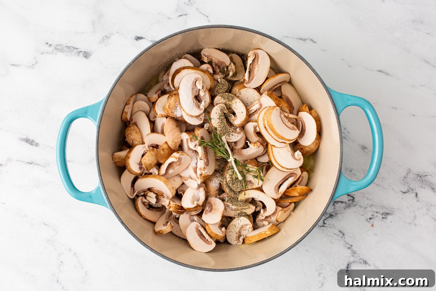 Sliced mushrooms, garlic, and thyme simmering in a large Dutch oven, releasing their liquid.