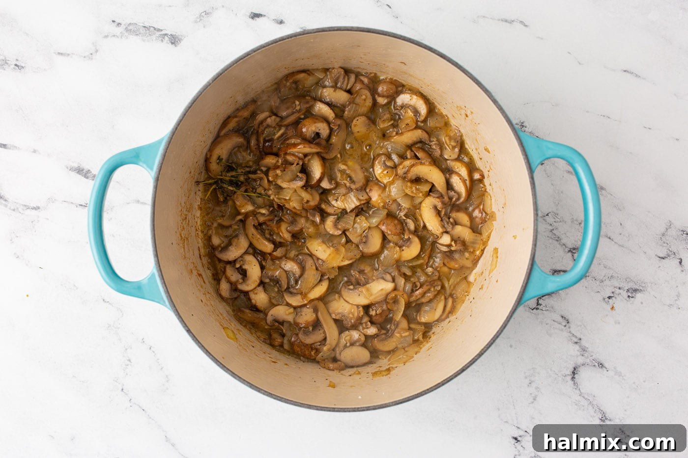 Mushroom mixture continuing to simmer, with the liquid visibly reduced and flavors intensifying.