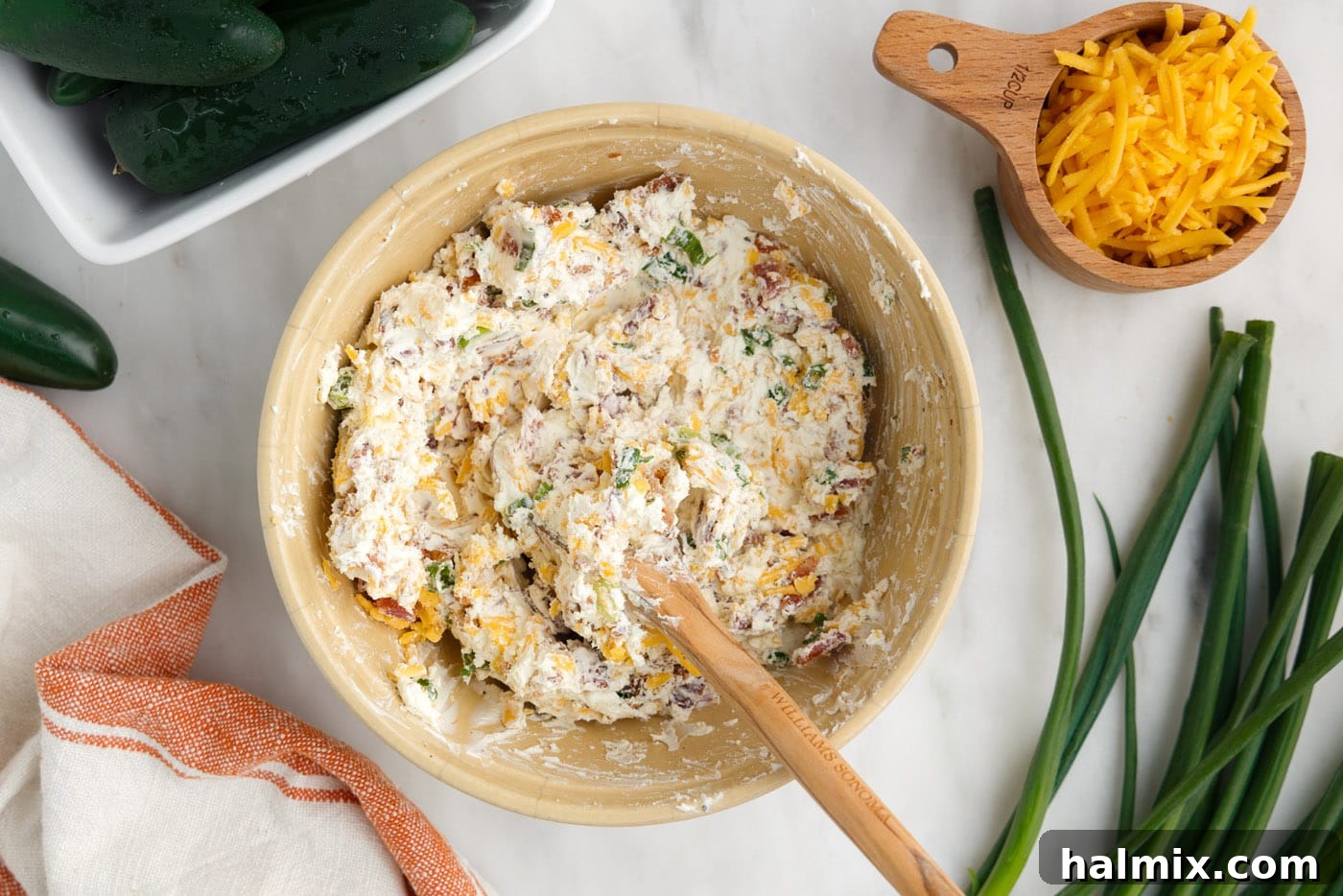 cream cheese, cheddar cheese, green onion, seasonings, and bacon mixed in a bowl