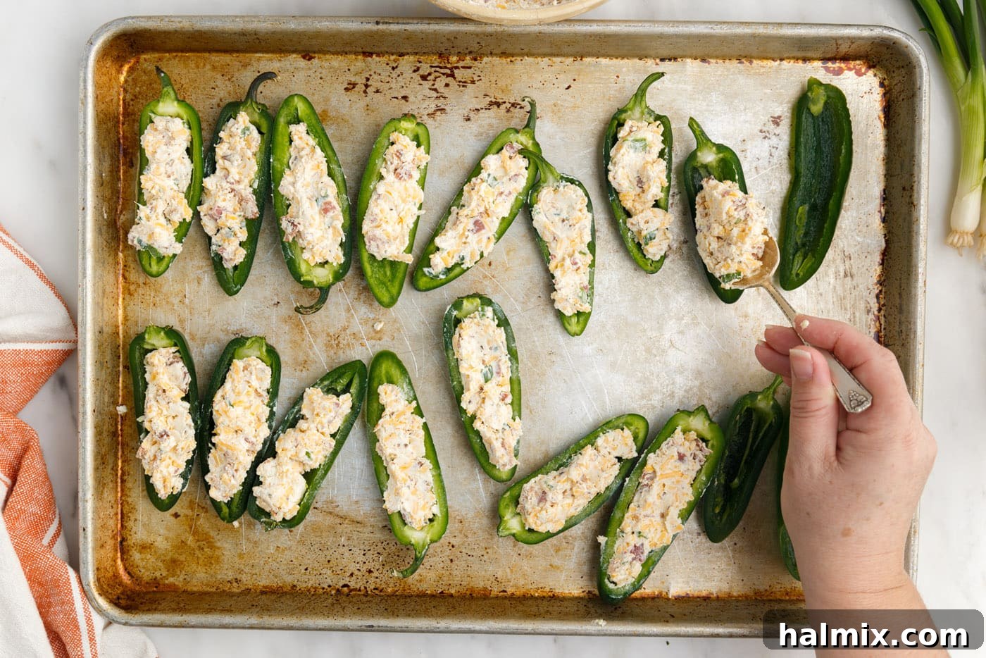 jalapeno poppers with cream cheese and cheddar on baking sheet