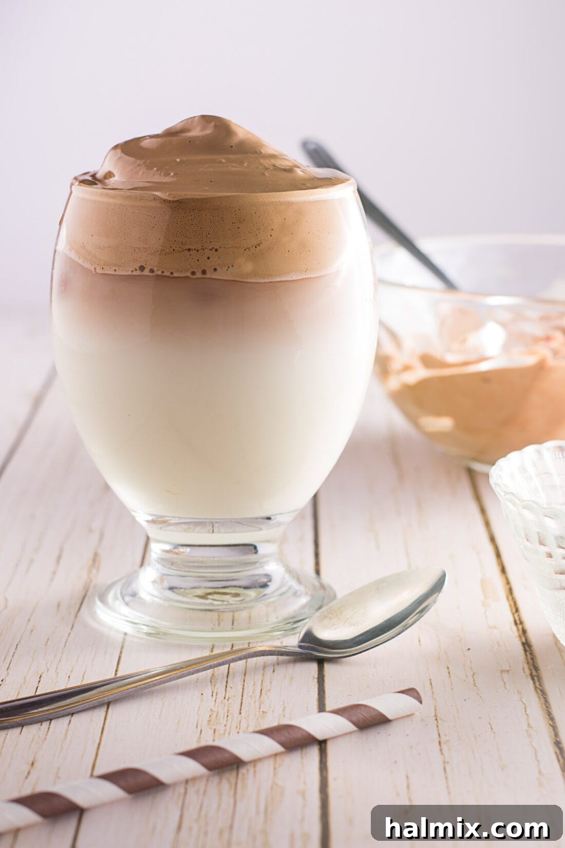 Dalgona Coffee with straw, showcasing the frothy whipped topping over milk.