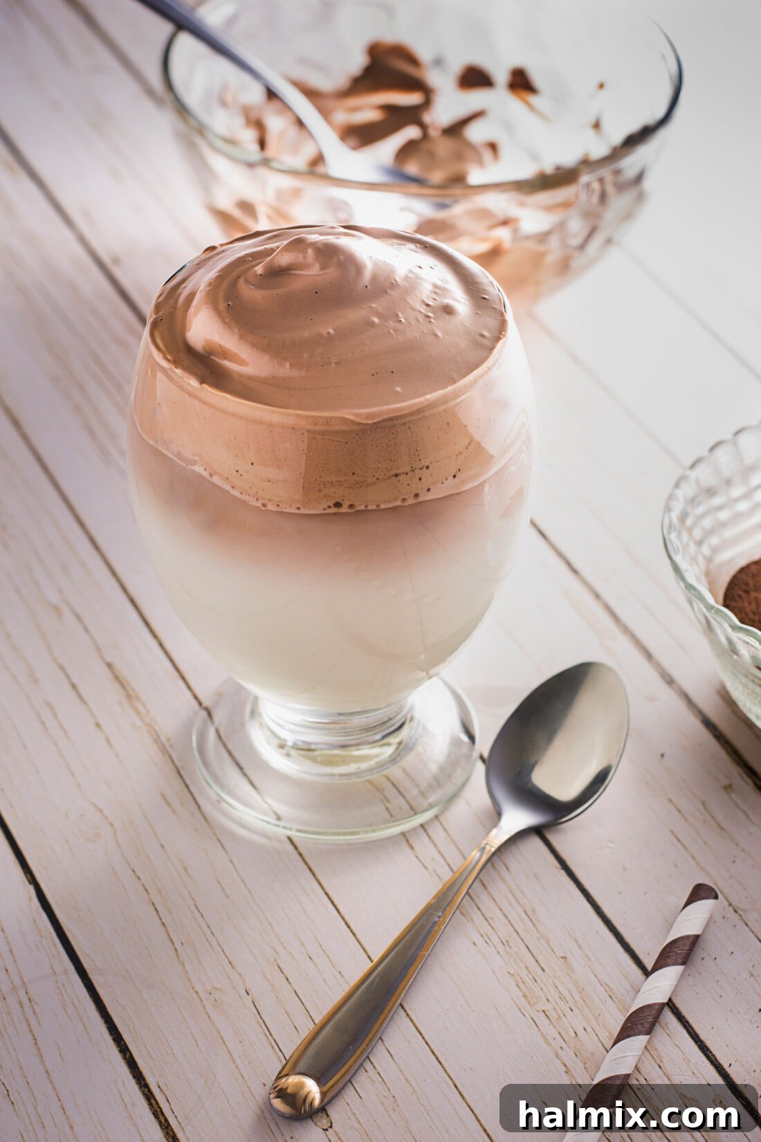 A close-up of Dalgona Coffee with a spoon, highlighting the thick, creamy foam.
