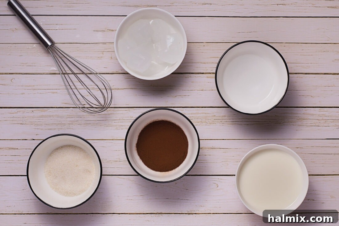 Instant coffee, granulated sugar, and a small jug of water on a wooden surface, the key ingredients for Dalgona coffee.