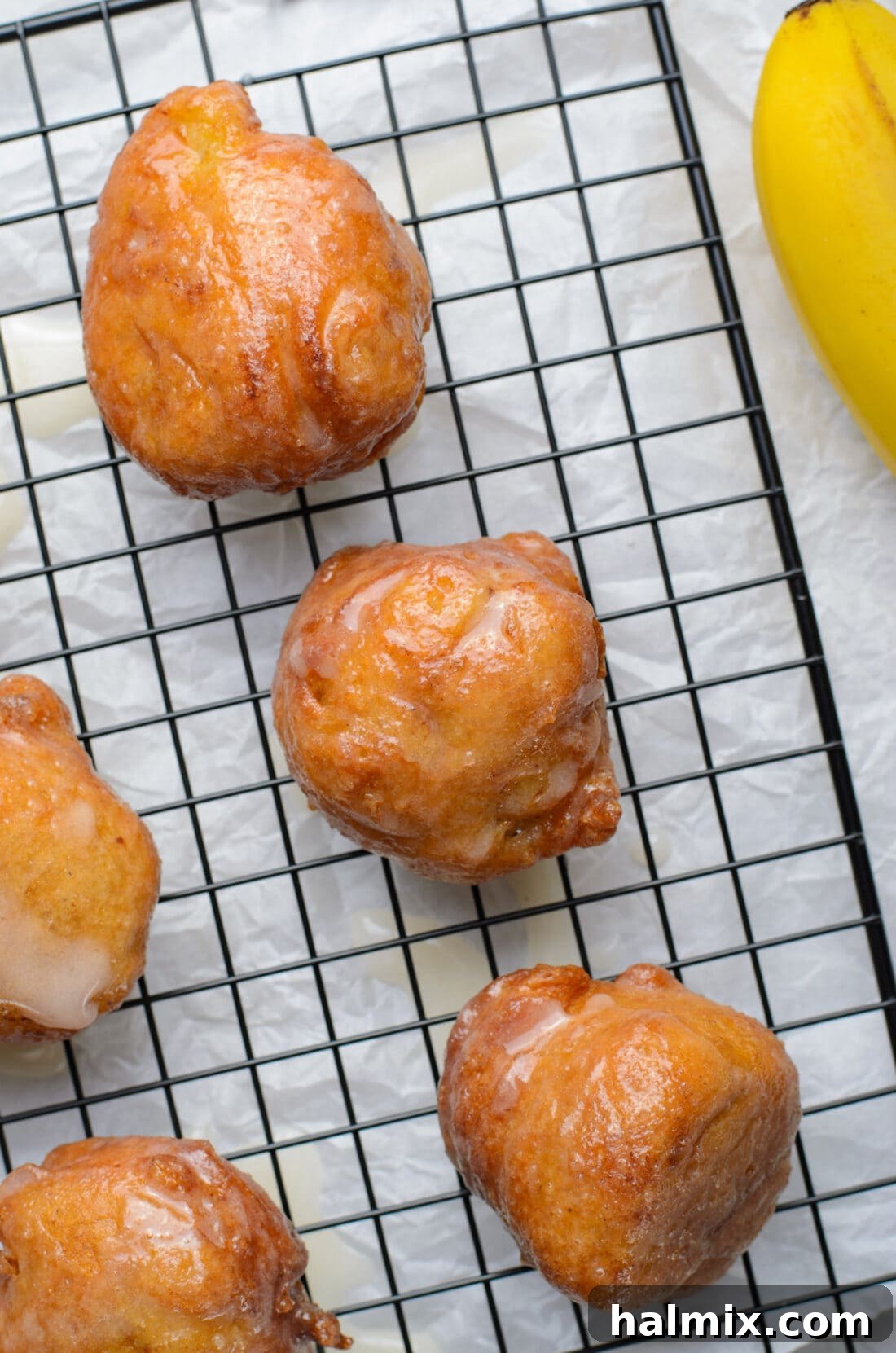 Freshly made and glazed banana fritters cooling on a wire rack.