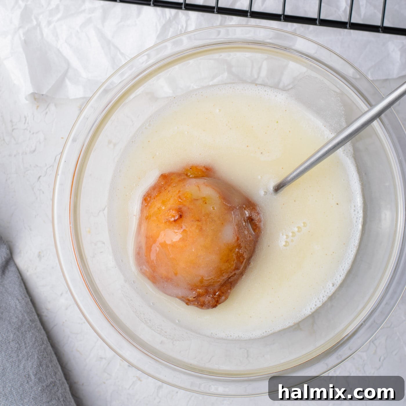 Dunking a banana fritter into a smooth sugar glaze.