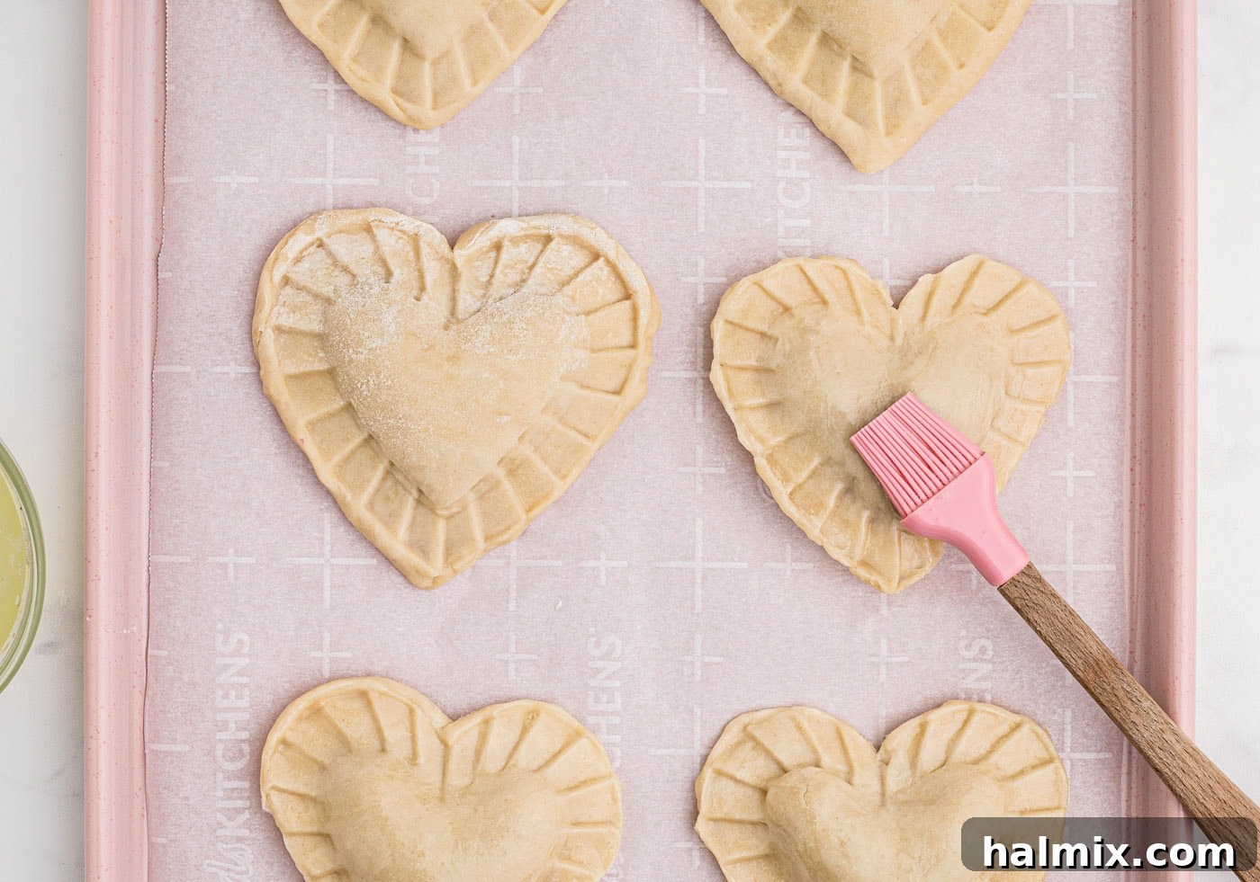 brushing egg wash over heart shaped cherry hand pies