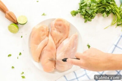 Woman poking chicken breasts with a knife to help marinade penetrate.