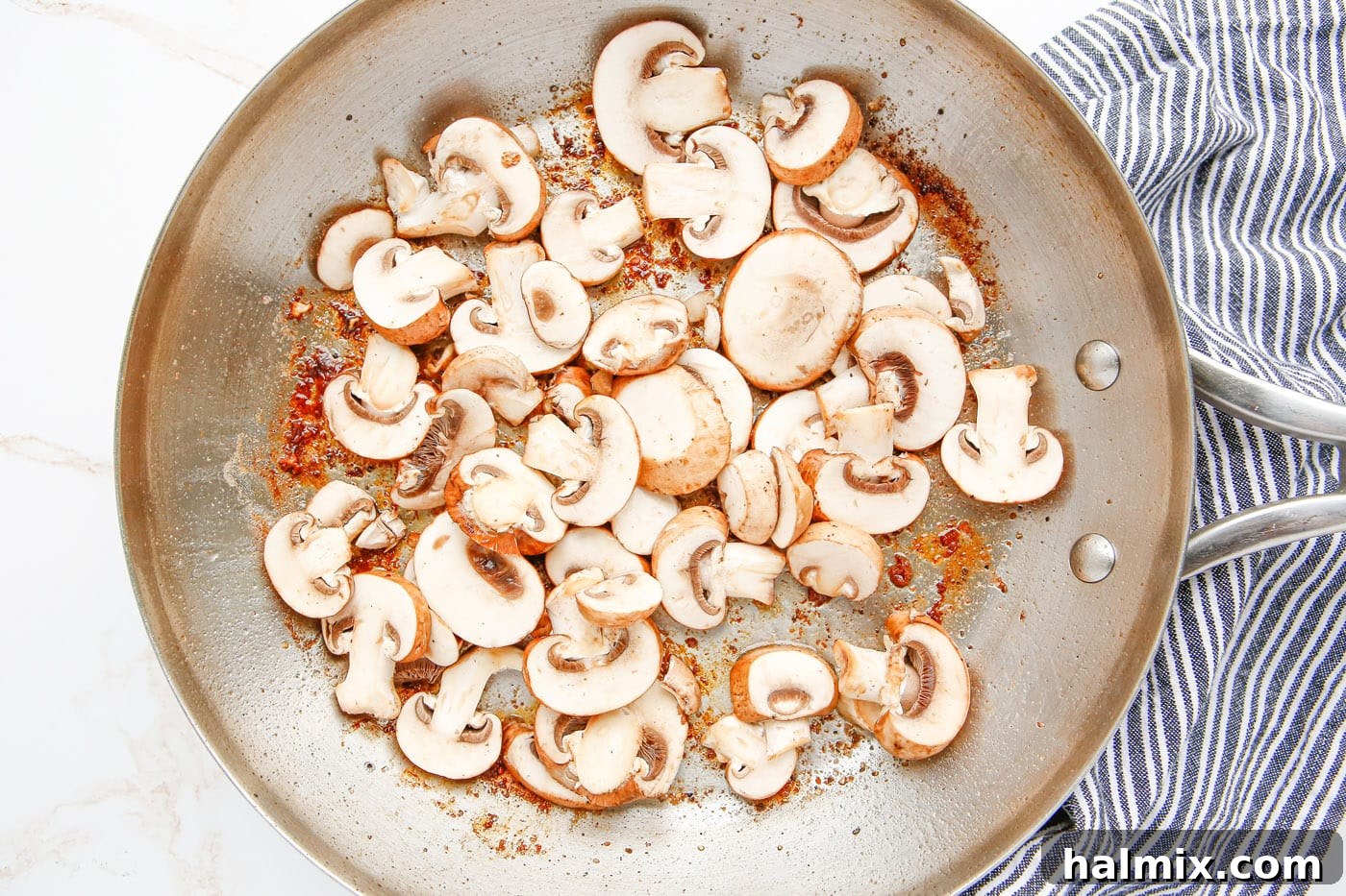 Sliced cremini mushrooms sautéing in butter in a hot skillet.