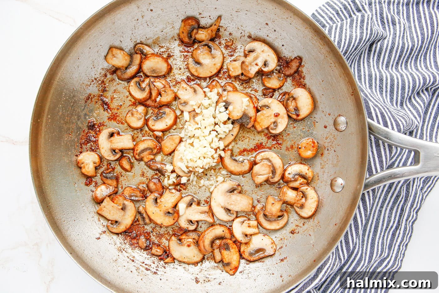 Mushrooms and minced garlic cooking together in a skillet, releasing their aroma.