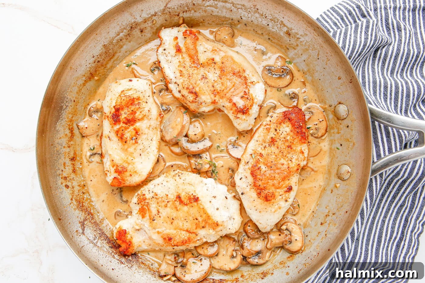 Final dish of pan-fried Chicken Marsala, glistening with creamy sauce and mushrooms.