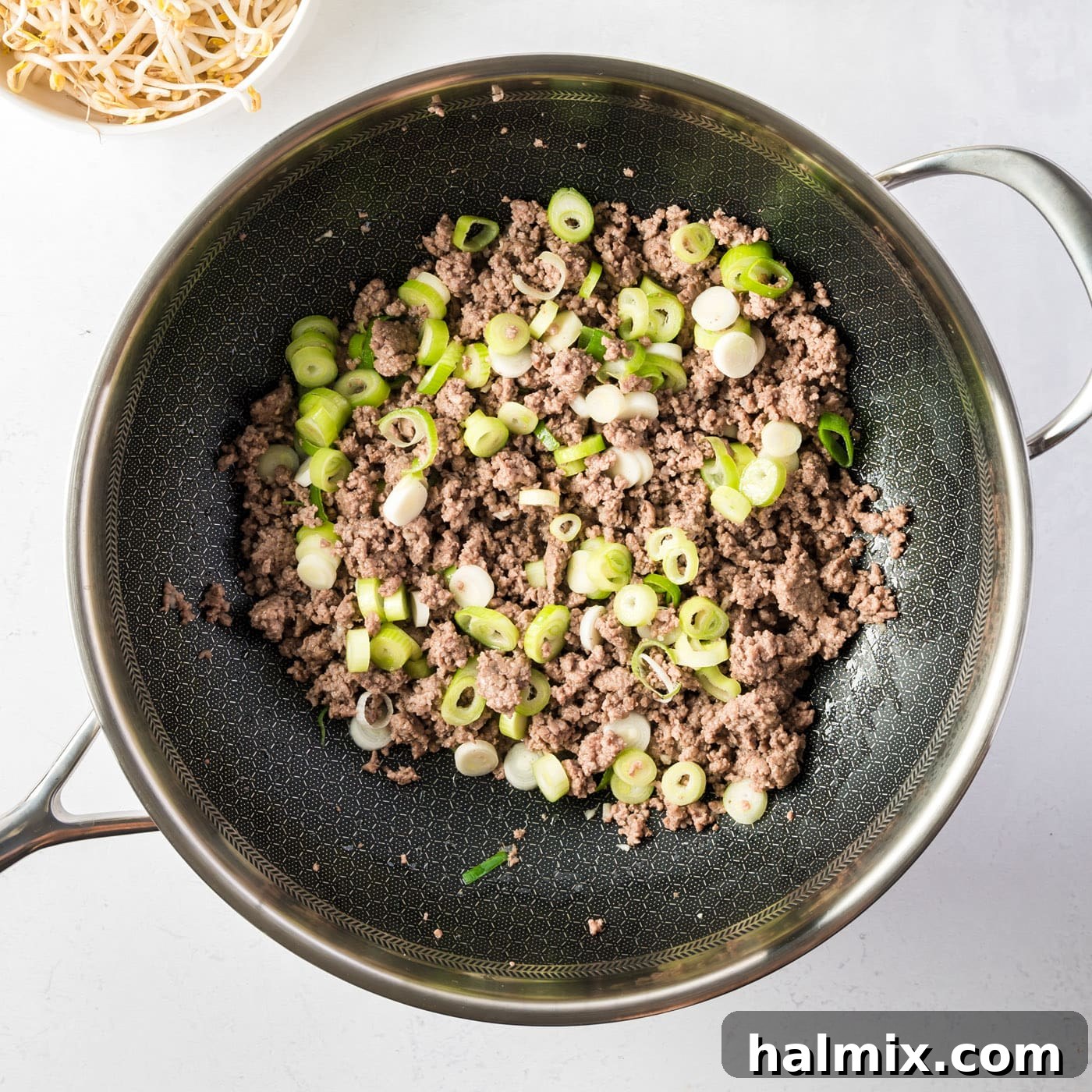 Ground beef, spring onions, and garlic cooking in a skillet