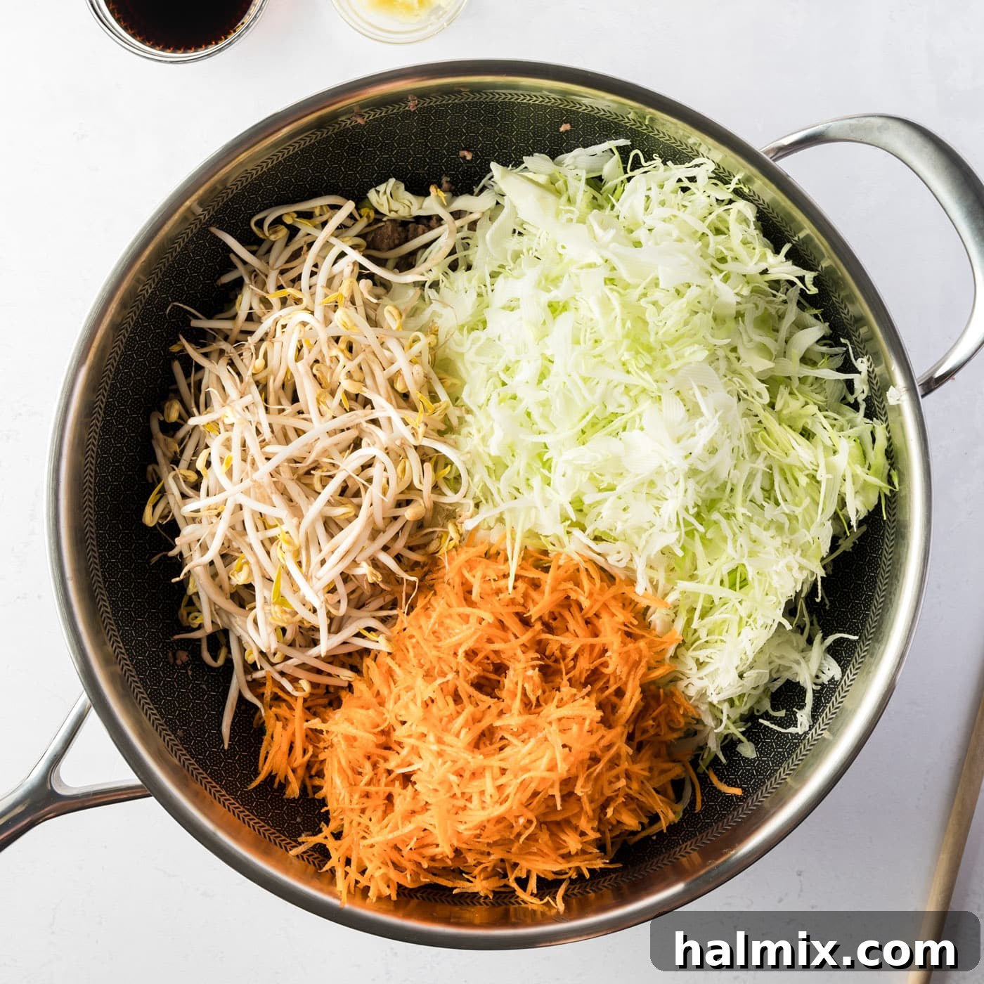 Cabbage, carrots, and mung bean sprouts added to the skillet with cooked meat
