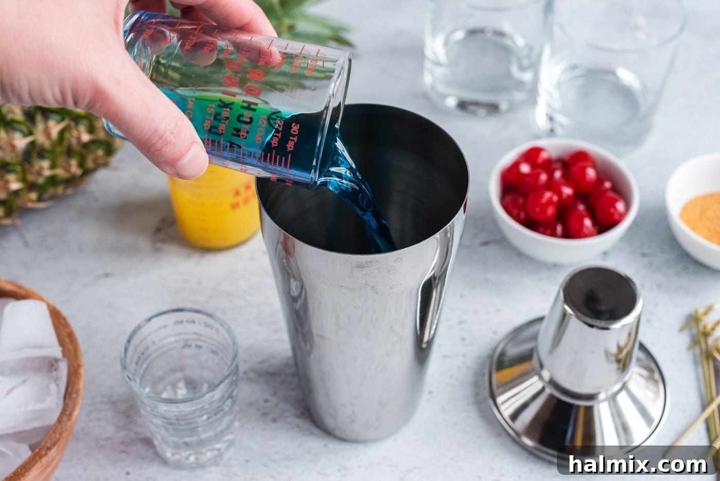 pouring blue curacao into cocktail shaker