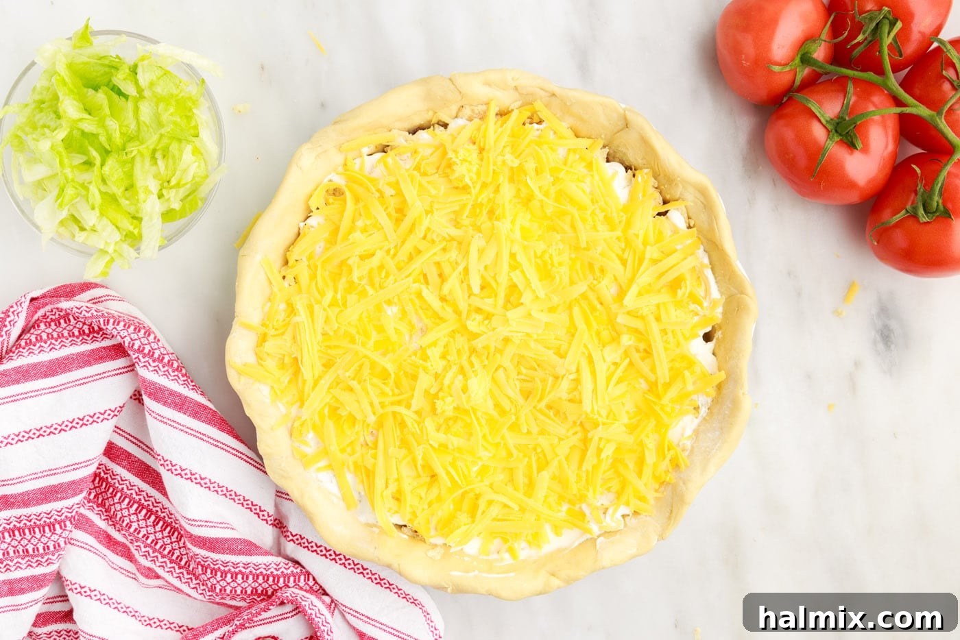 Ultimate Taco Casserole 12 The final layer of shredded cheese being sprinkled over the top of the taco pie before baking.