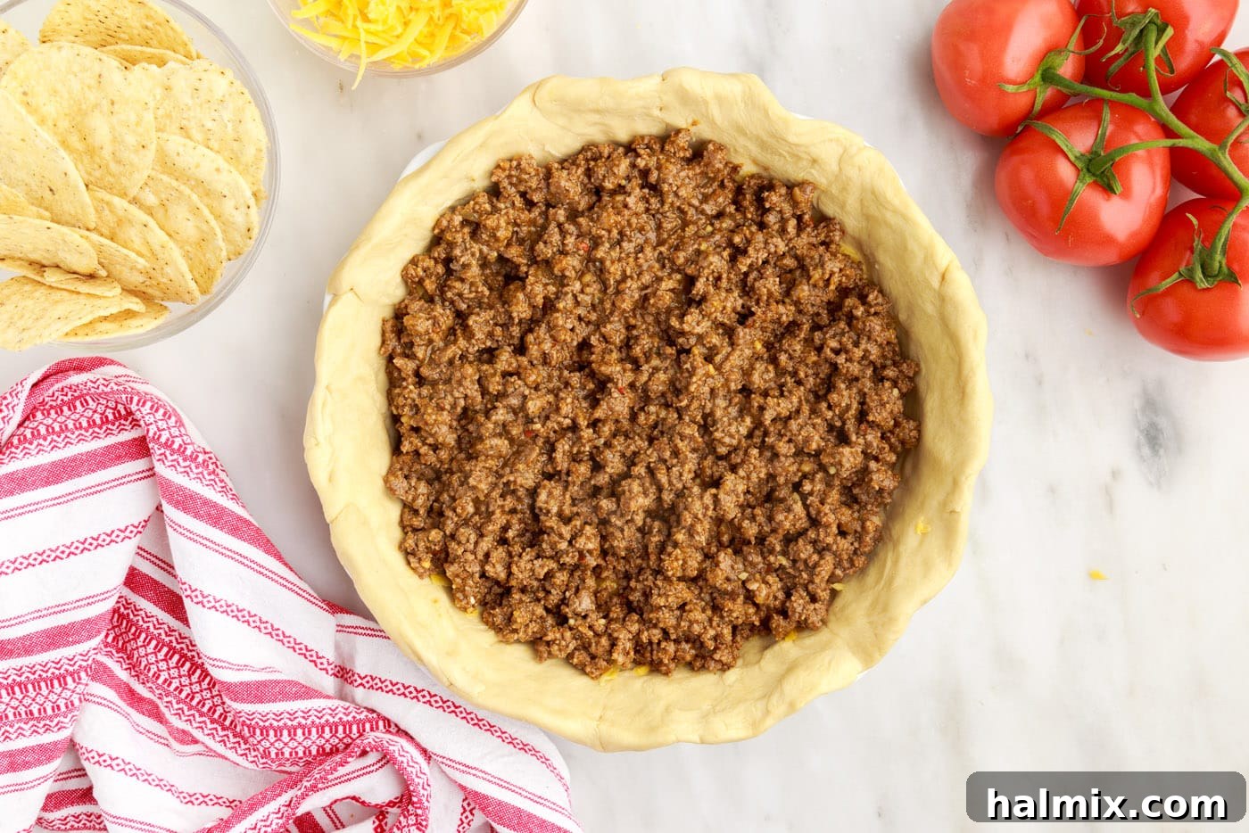 Ultimate Taco Casserole 8 Seasoned ground beef being spread over the cheese layer in the crescent roll pie crust.