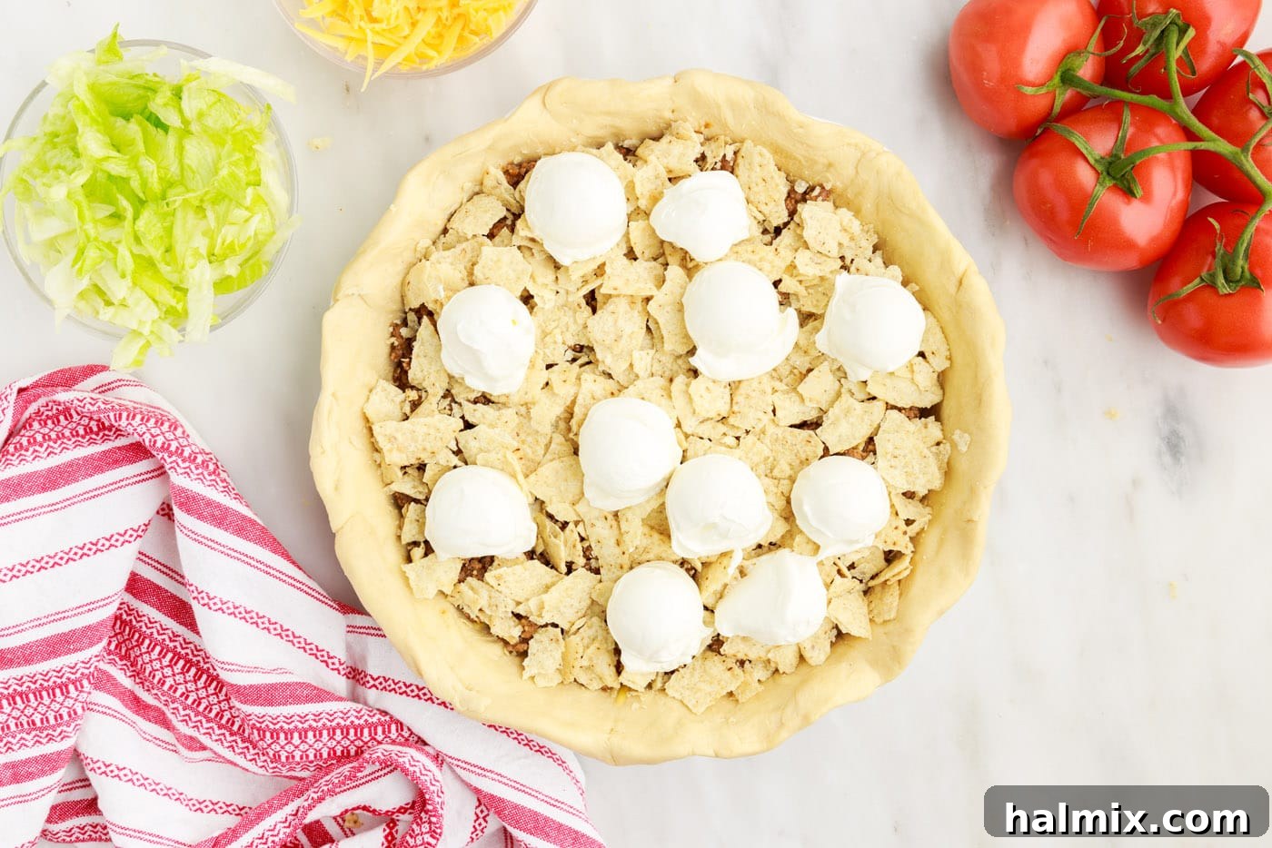 Ultimate Taco Casserole 10 Dollops of sour cream spread over the crushed tortilla chips and ground beef layer in the taco pie.